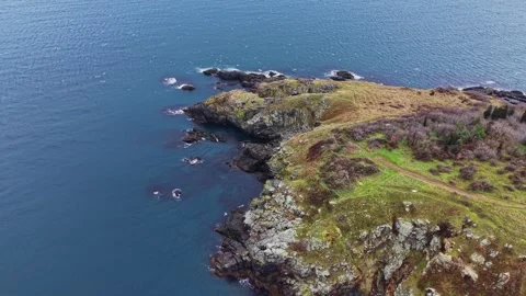 Coastline view with rocky cliffs and calm water under clear sky Stock Footage 335142857