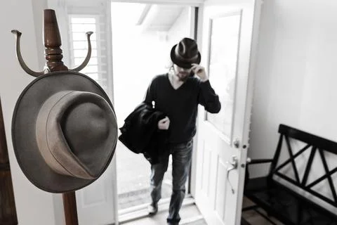 Coat Rack And Man Walking In Front Door Wearing Fedora Hat Blurred Background Stock Photos
