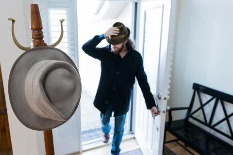 Coat Rack And Man Walking In Front Door Wearing Fedora Hat Blurred Background Foto stock