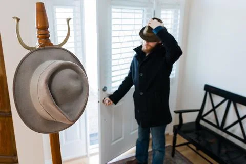 Coat Rack And Man Walking In Front Door Wearing Fedora Hat Blurred Background Foto stock