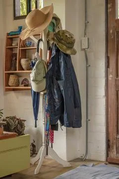 A coat rack with some umbrellas, assorted hats and a raincoat Stock Photos