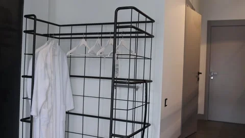 Coat rack with white hangers and hanging robes in a minimalist interior Stock Footage 313656514