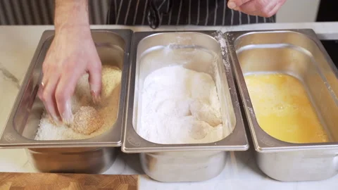 Coating chicken pieces in flour, breadcrumbs and egg. Stock Footage 239159590