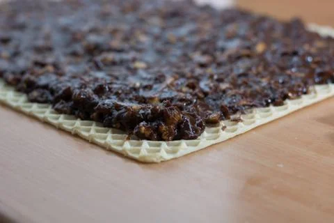 Coating chocolate topping with wallnuts on cake crust Stock Photos