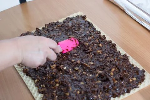 Coating chocolate topping with wallnuts on cake crust Stock Photos