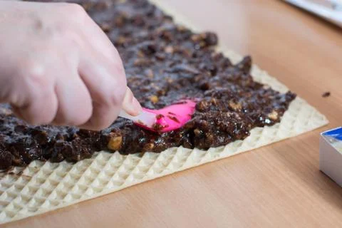 Coating chocolate topping with wallnuts on cake crust Stock Photos