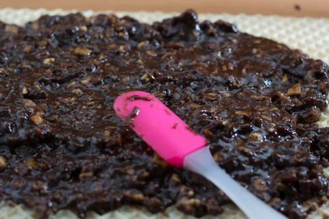Coating chocolate topping with wallnuts on cake crust Stock Photos