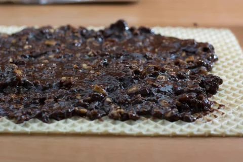 Coating chocolate topping with wallnuts on cake crust Stock Photos