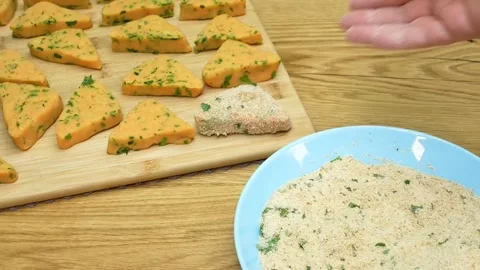 Coating triangle potato snacks in egg wash and breadcrumbs for crispy frying Stock Footage 325071905