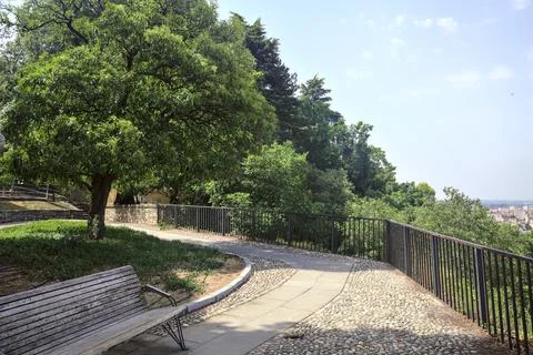 Cobbled path and flowerbed with trees on a viewpoint in a castle above a city Stock Photos