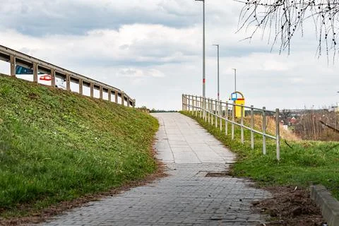 Cobbled pedestrian and bicycle path leading up a slope next to a road Фото