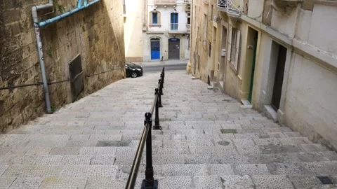 Cobbled stepped ramp winds through valletta cars parked along the historic old Stock Footage 341805595