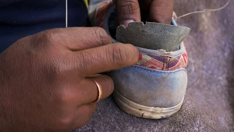 A cobbler sitting by the roadside pavement Stock Footage 75265308