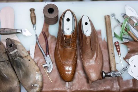 Cobblers workbench with leather shoes, tools, and sewing materials in a detailed Stock Photos