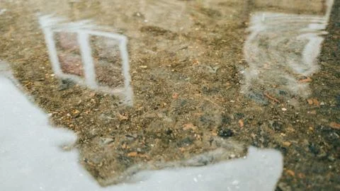 A Cobblestone Building Reflecting in a Puddle Stock Photos