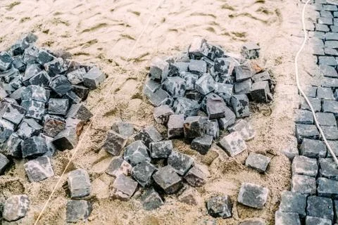 Cobblestone granite blocks on sand path. Construction of road with details Stock Photos