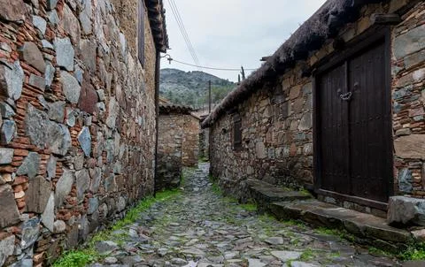Cobblestone path aged stone walls and traditional buildings in a rural vill.. Stock Photos