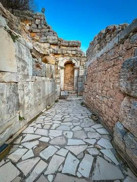 Cobblestone Path Cuts through Ephesus Ruins to Shadowed Arched Portal Fotos de archivo
