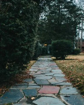 A Cobblestone Path Leading Up To The Front Door of a Home With Trees and Bush Stock Photos