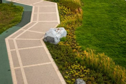 Cobblestone path winding through a lush green park with decorative stone 스톡 사진