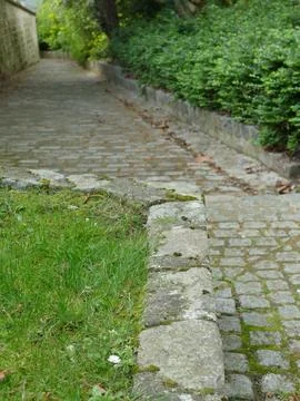 Cobblestone path winding through a peaceful garden cemetery with stone wall.. Foto stock