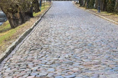 Cobblestone path winding uphill through a park with trees and grass 스톡 사진