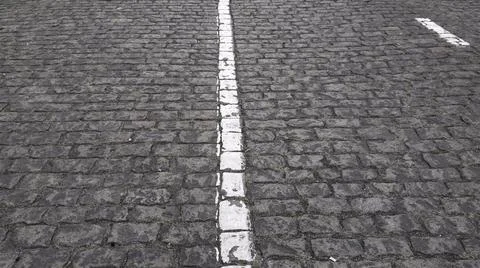 Cobblestone paved road texture with white road marking Stock Photos