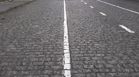 Cobblestone paved road texture with white road marking 스톡 사진
