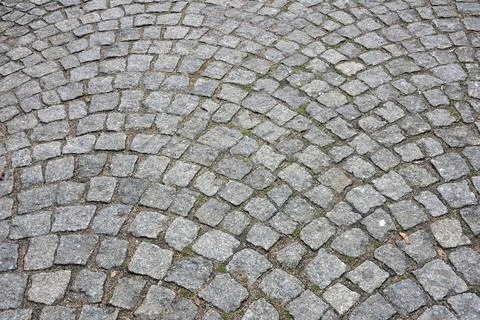 Cobblestone pavement with a curved pattern, featuring gray stones and patch.. 스톡 사진