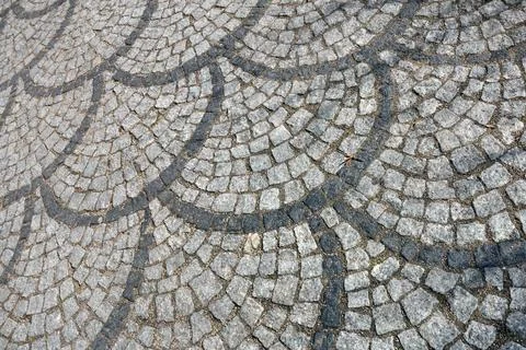 Cobblestone pavement features a unique pattern of gray stones arranged in cur Stock Photos