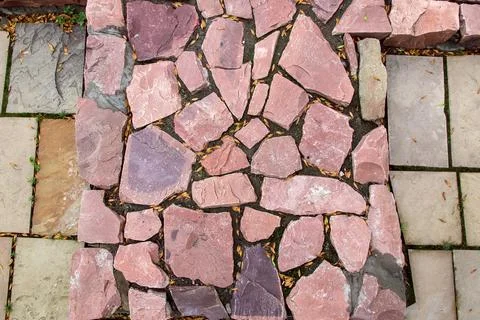 Cobblestone pavement made of red rough stone, texture top view. Stock Photos