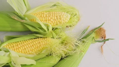 Cobs of fresh yellow corn with green leaves lie on kitchen table top view Stockbeeldmateriaal 218147700