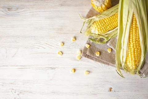Cobs of ripe raw corn on white wooden background, space for text. Flat lay. Foto stock