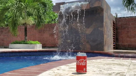 Coca cola lying on the edge of the swimming pool with blue water and cascade. Stock Footage 165232984