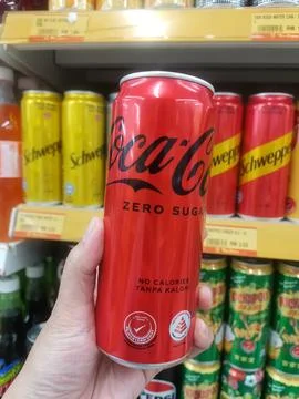 Coca-Cola Zero Sugar Can On Store Shelf With Schweppes Cans In Background Stock Photos