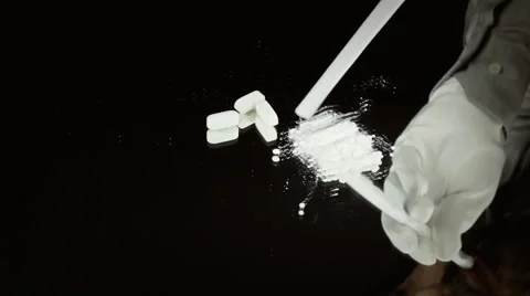 Cocaine on a glass with a sniffer and a knife on a black background Stock  Photo