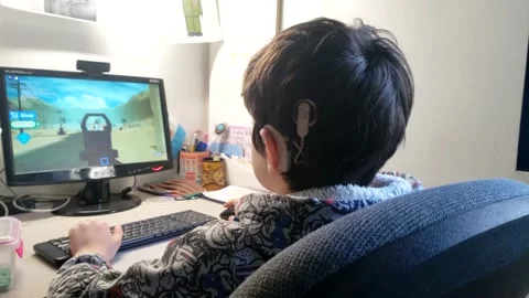 Cochlear implant Child playing roblox with computer 1 Stock Footage 138477385
