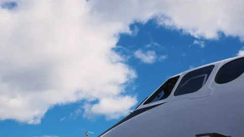 Cockpit of white with black stripes aircraft against blue daytime cloudy sky. In Stock Footage 225433173
