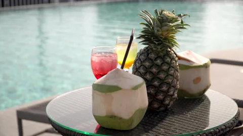 Cocktail and fruit pineapple , coconut on table by swimming pool in clubhouse Stock Footage 146316878