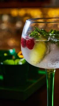 Cocktail experience featuring chilled gin and tonic with raspberries, mint, and Stock Photos