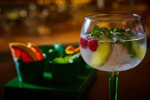 Cocktail experience featuring chilled gin and tonic with raspberries, mint, and Stock Photos