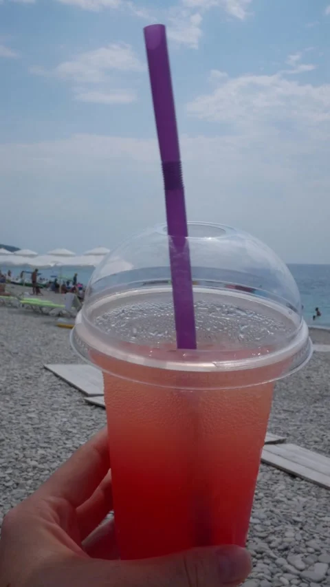 Cocktail in hand against the backdrop of the beach and blue sea. Cocktail Stock Footage 312867467