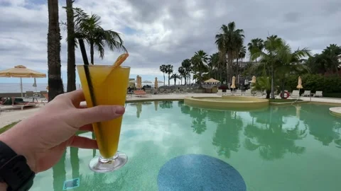 Cocktail in a man's hand on the background of the pool Video stock 240184594