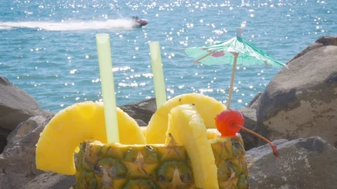 Cocktail Served in a Fresh Pineapple with the Ocean Sparkling in the Background Stock Footage 98273159