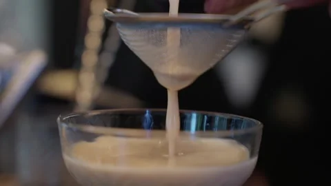 Cocktail strained through mesh sieve into coupe glass close up Video stock 328088646