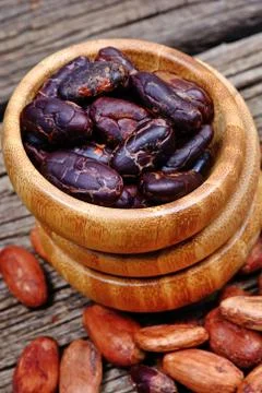 Cocoa beans in a bowl on rustic table Stock Photos