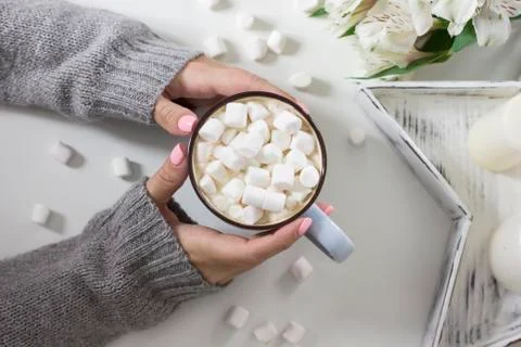 Cocoa with marshmallows in female hands on white background flowers, candles, Stock Photos