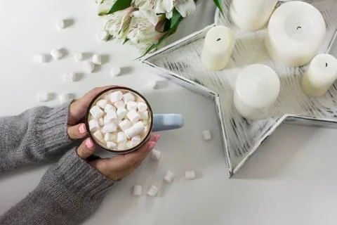 Cocoa with marshmallows in female hands on white background flowers, candles, Stock Photos