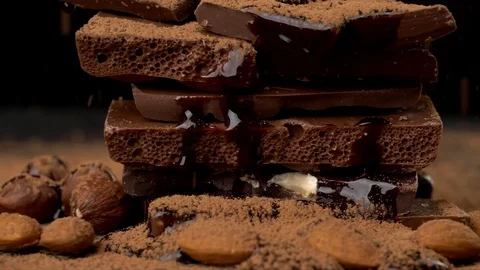 Cocoa powder falling onto heap of various chocolate pieces and nuts Stock-Footage 78590842