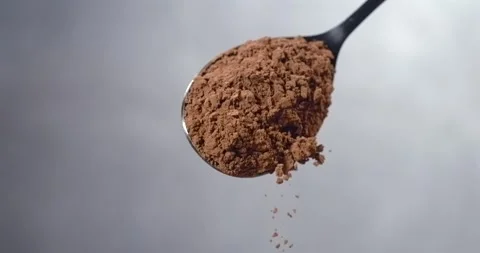Cocoa powder falling from spoon chocolate dust cloud slow motion Stock Footage 344849020